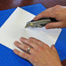 A hobby knife scoring a white styrene sheet to demonstrate the clean score and snap method for precise plasticard cutting.