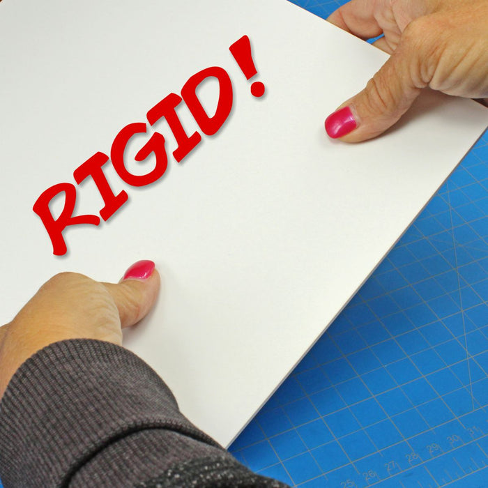Hands attempting to bend a thick 0.100-inch white styrene plasticard sheet to demonstrate the rigidity of the material, overlaid with the word "RIGID!" in red text.